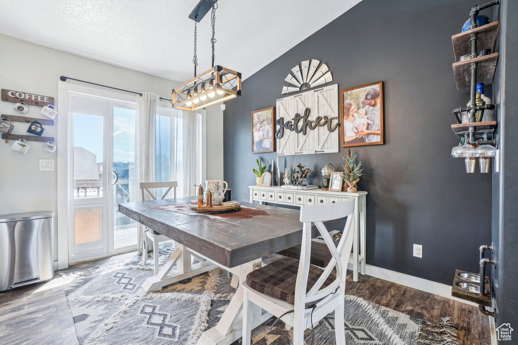 Dining room featuring a chandelier, wood finished floors, baseboards, and a textured ceiling