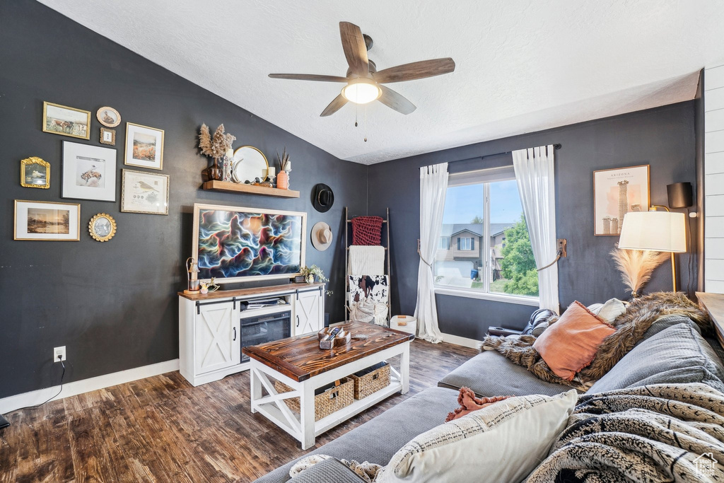 Living room with baseboards, dark wood-style flooring, a ceiling fan, and vaulted ceiling