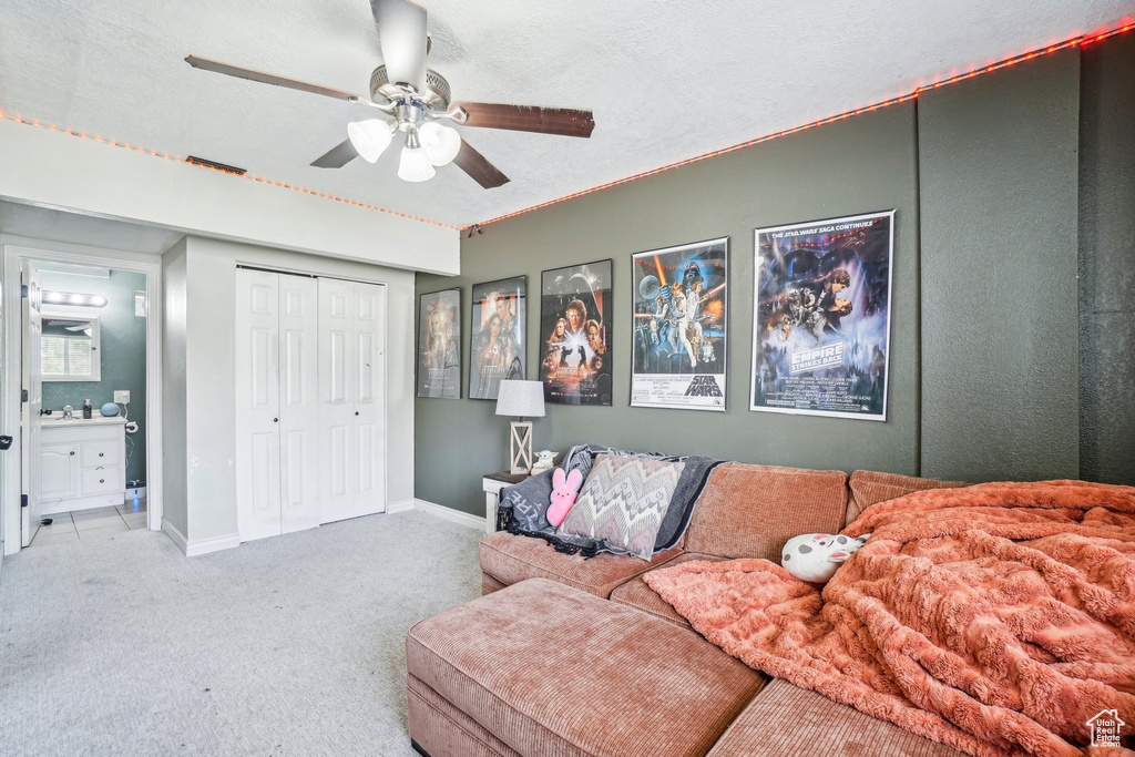 Carpeted living area featuring a ceiling fan and baseboards