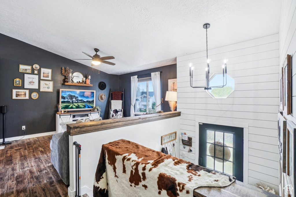 Living room featuring dark wood finished floors, a textured ceiling, ceiling fan, a chandelier, and baseboards