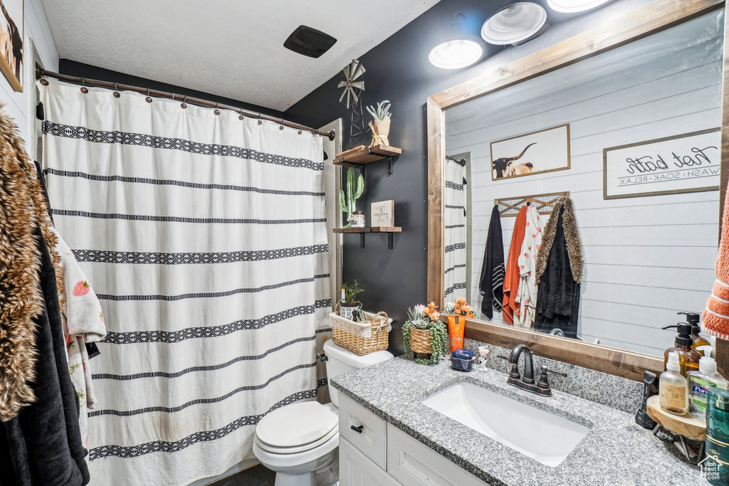 Bathroom with toilet, vanity, and a shower with shower curtain