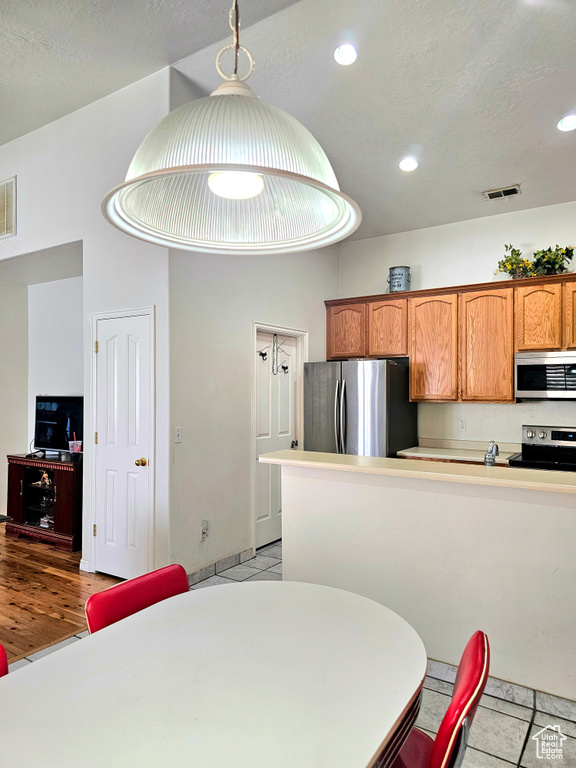 Kitchen with appliances with stainless steel finishes, brown cabinets, recessed lighting, and light countertops
