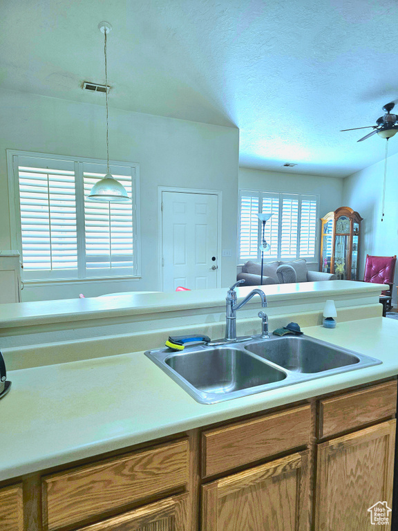 Kitchen featuring open floor plan, a ceiling fan, light countertops, a textured ceiling, and hanging light fixtures