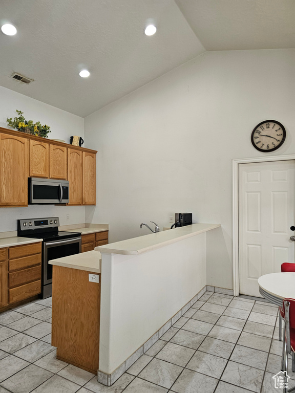 Kitchen featuring appliances with stainless steel finishes, lofted ceiling, light countertops, recessed lighting, and light tile patterned flooring