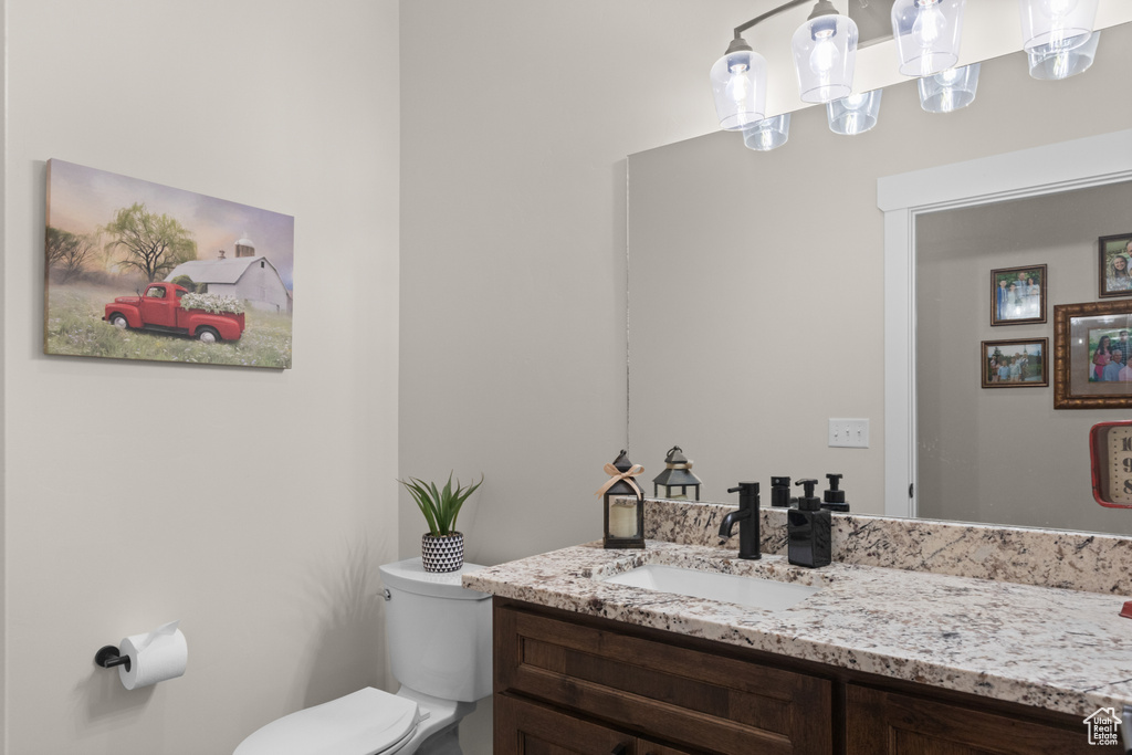Bathroom with toilet, vanity, and a chandelier