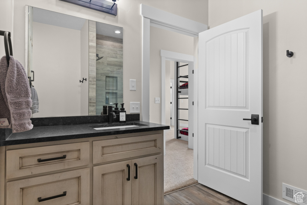 Bathroom featuring a stall shower, wood finished floors, and vanity