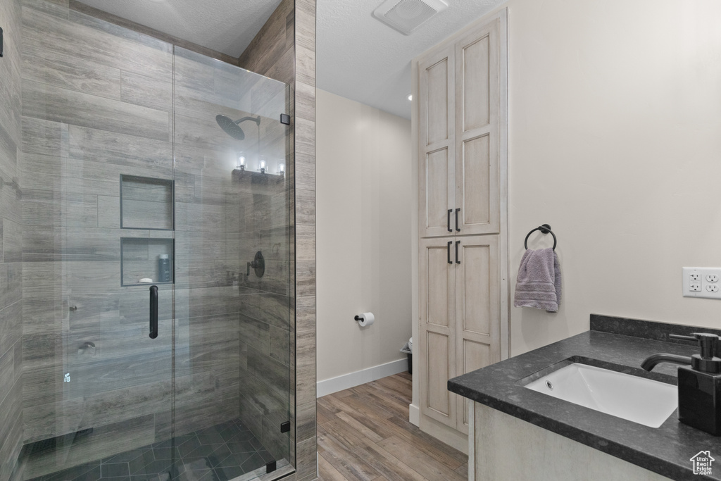 Bathroom with wood finished floors, a stall shower, baseboards, vanity, and toilet