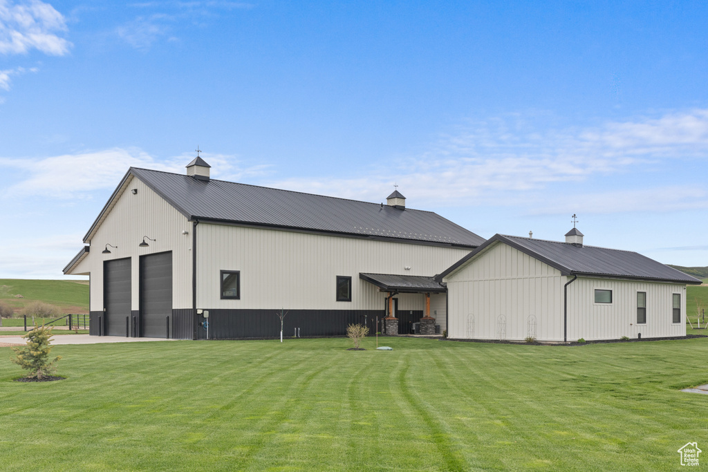 Back of house with a pole building, a lawn, an outdoor structure, and metal roof