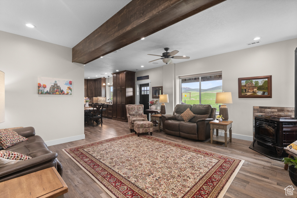 Living room featuring a wood stove, baseboards, wood finished floors, recessed lighting, and ceiling fan