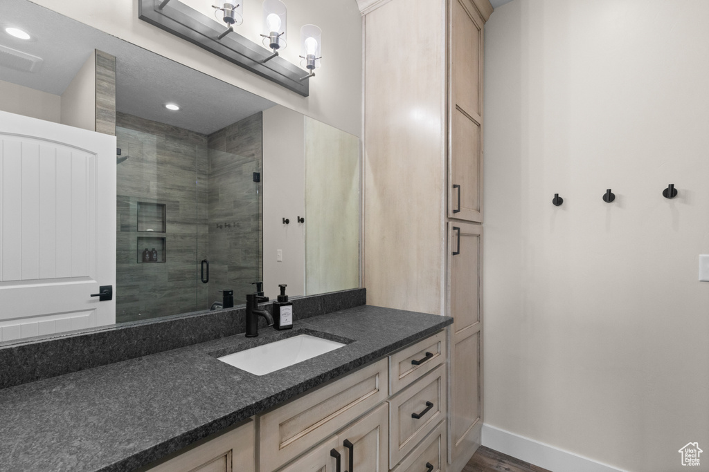 Bathroom featuring a shower stall, vanity, recessed lighting, baseboards, and wood finished floors