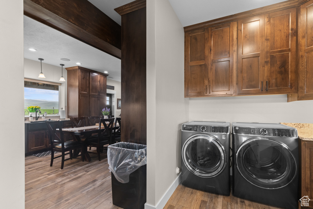 Laundry room with independent washer and dryer, wood finished floors, cabinet space, baseboards, and recessed lighting