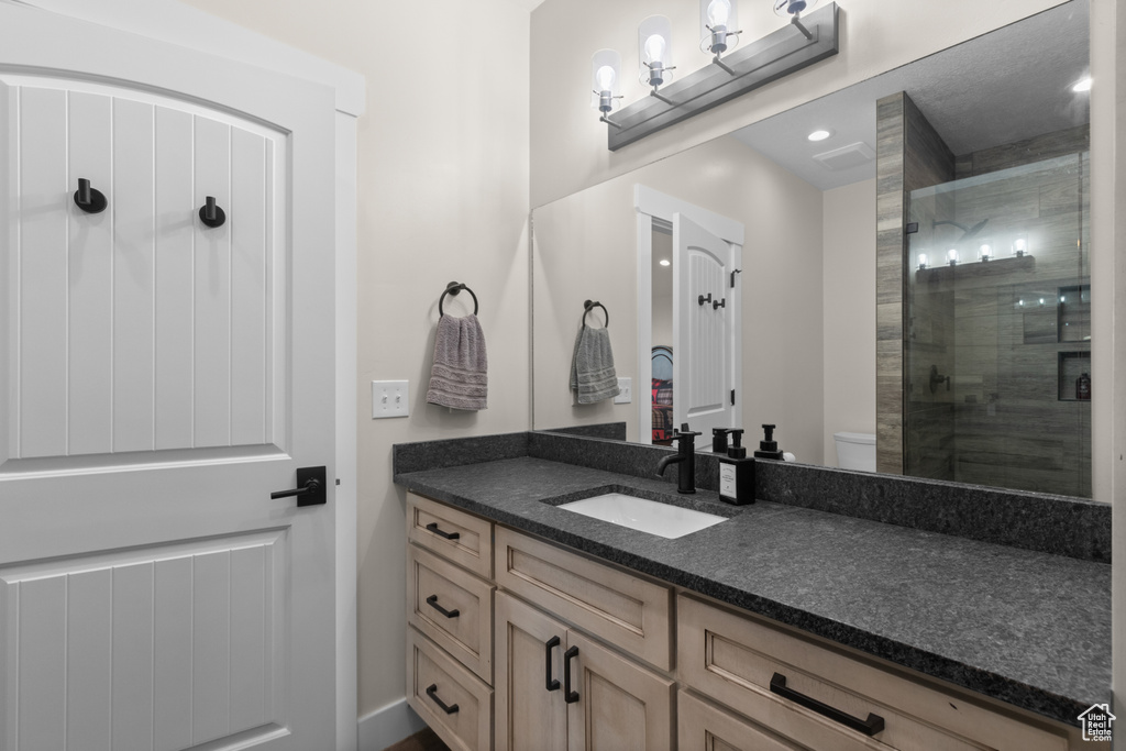 Bathroom with a shower stall, vanity, toilet, and recessed lighting