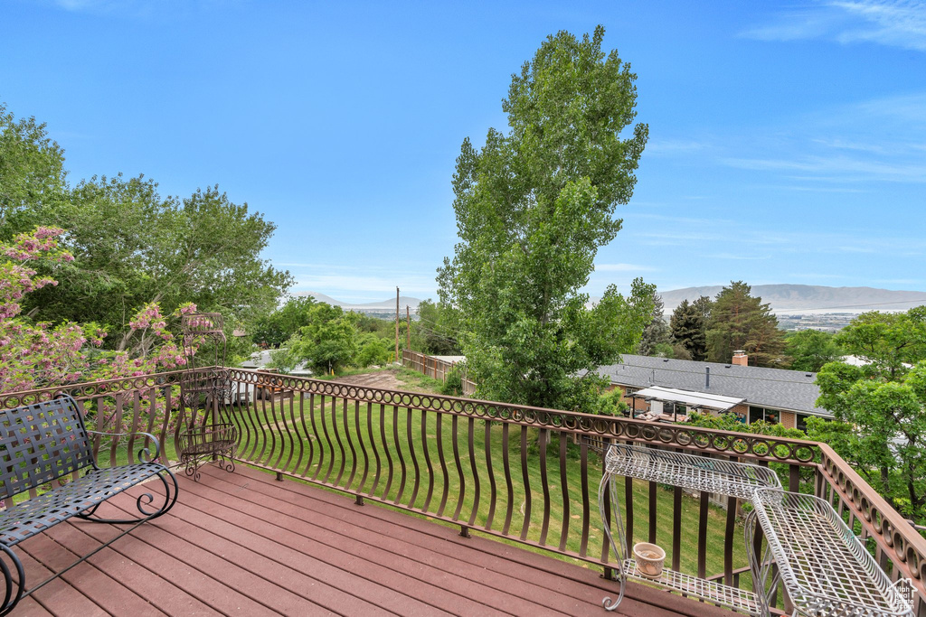 Wooden deck featuring a mountain view and a yard