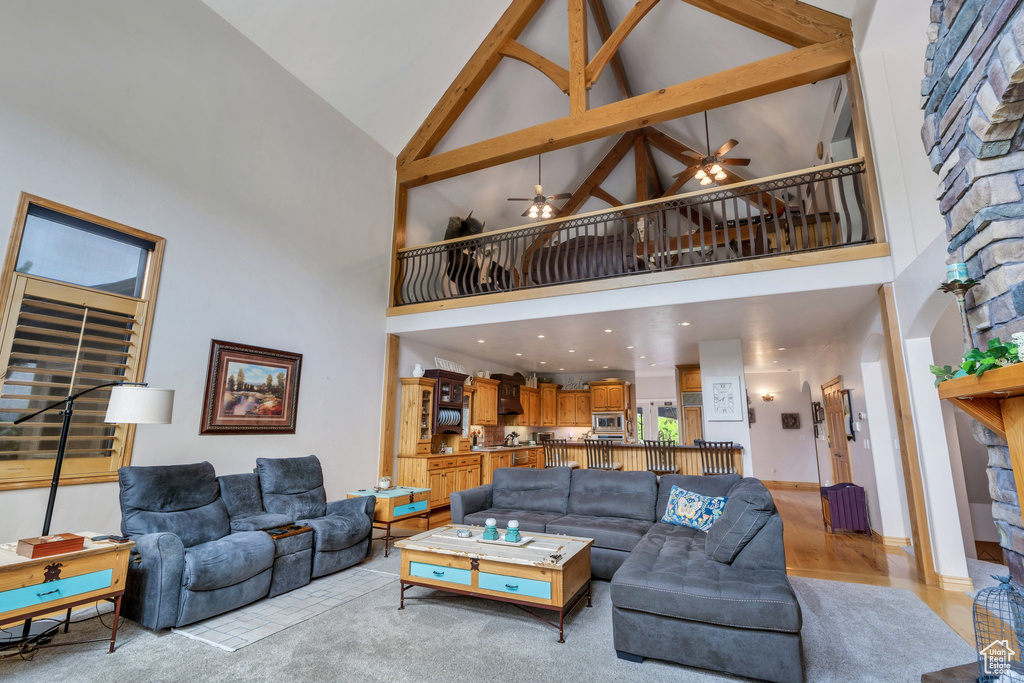 Living room with high vaulted ceiling, a ceiling fan, and light wood-style floors
