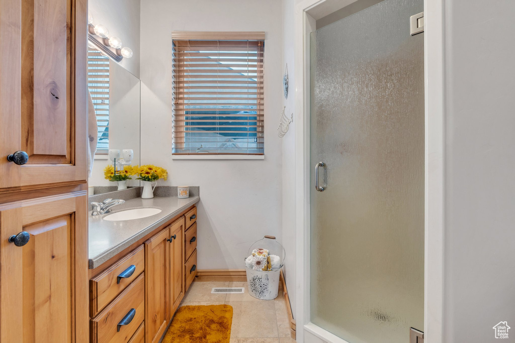 Full bathroom featuring a shower stall, vanity, tile patterned flooring, and baseboards