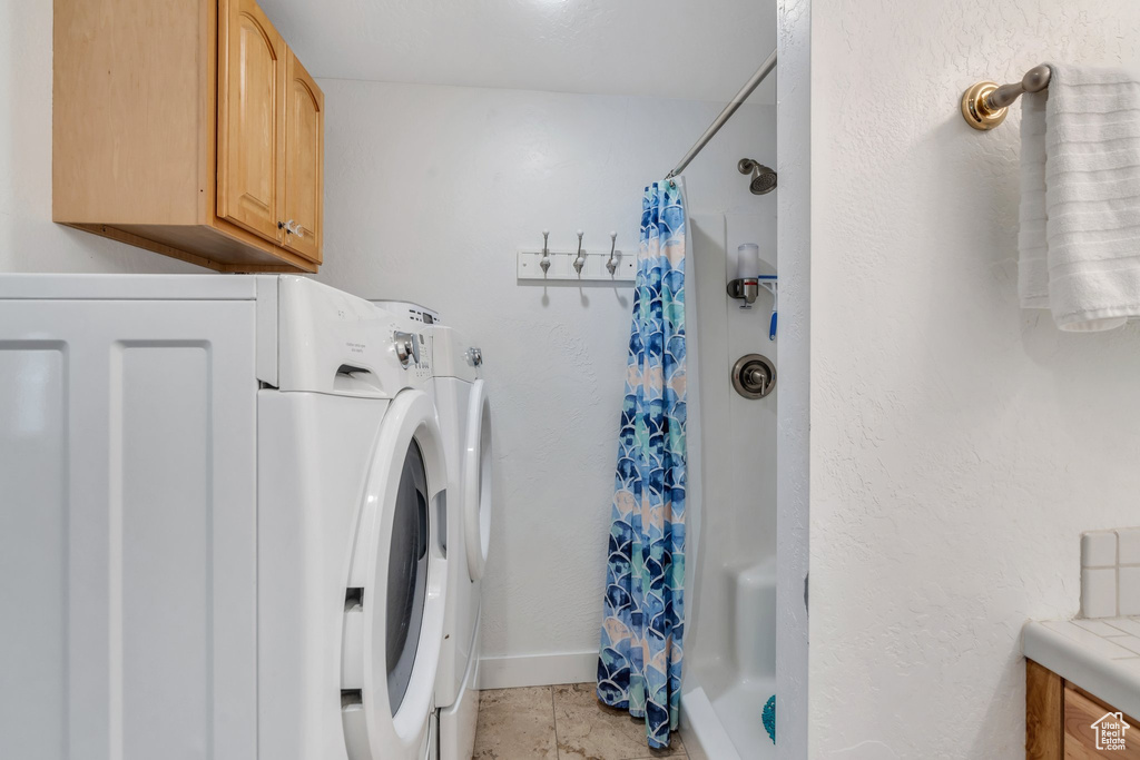 Washroom featuring washer and dryer, cabinet space, and baseboards