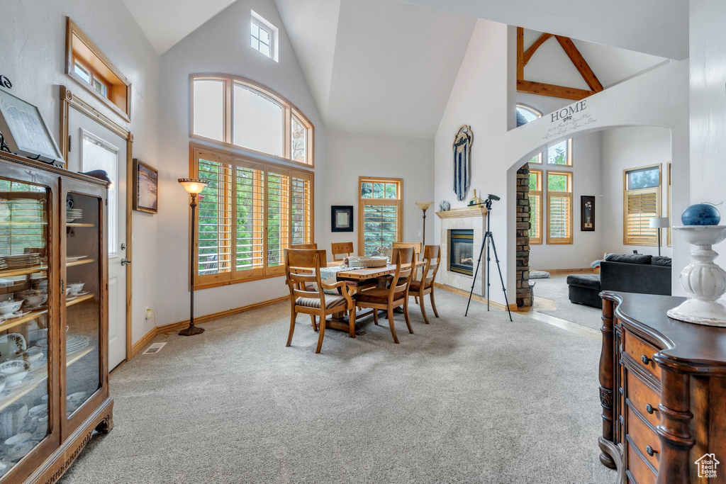 Carpeted dining room featuring high vaulted ceiling, healthy amount of natural light, baseboards, and a tile fireplace