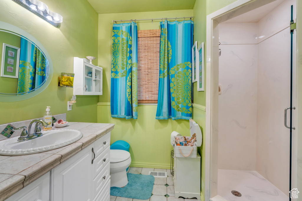 Full bathroom featuring a stall shower, tile patterned floors, vanity, toilet, and baseboards