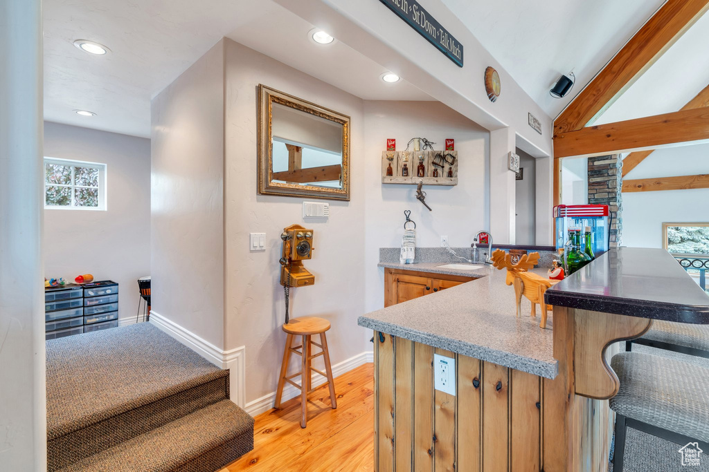 Bar area with a sink, healthy amount of natural light, recessed lighting, light wood-type flooring, and baseboards