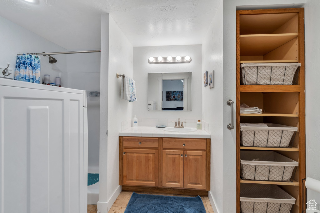 Full bath featuring baseboards, a shower with curtain, vanity, and tile patterned floors