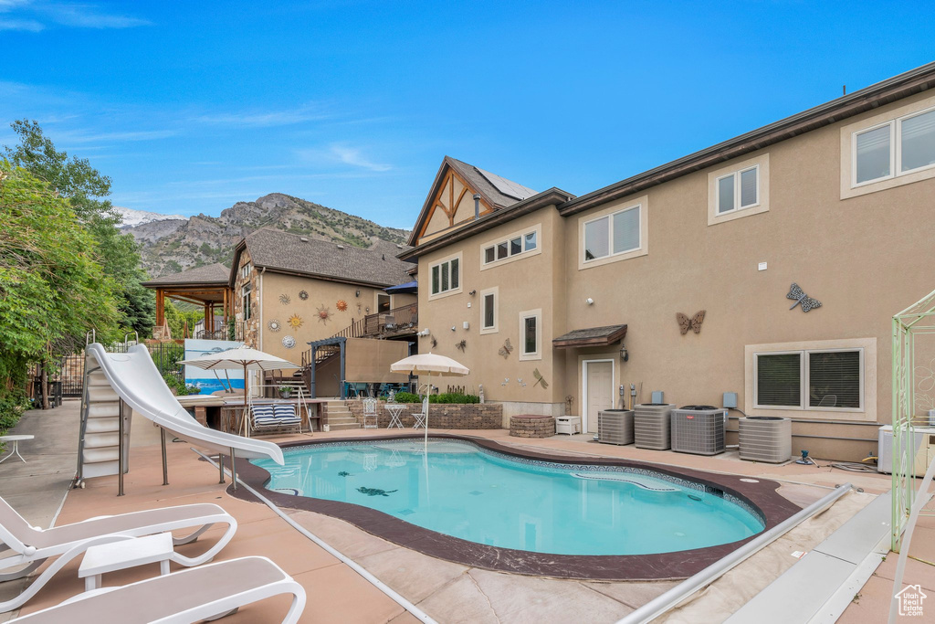 View of pool with a water slide, a mountain view, a patio area, and cooling unit