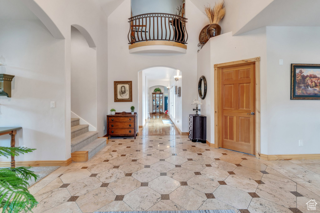 Entryway with arched walkways, stairs, a towering ceiling, and baseboards
