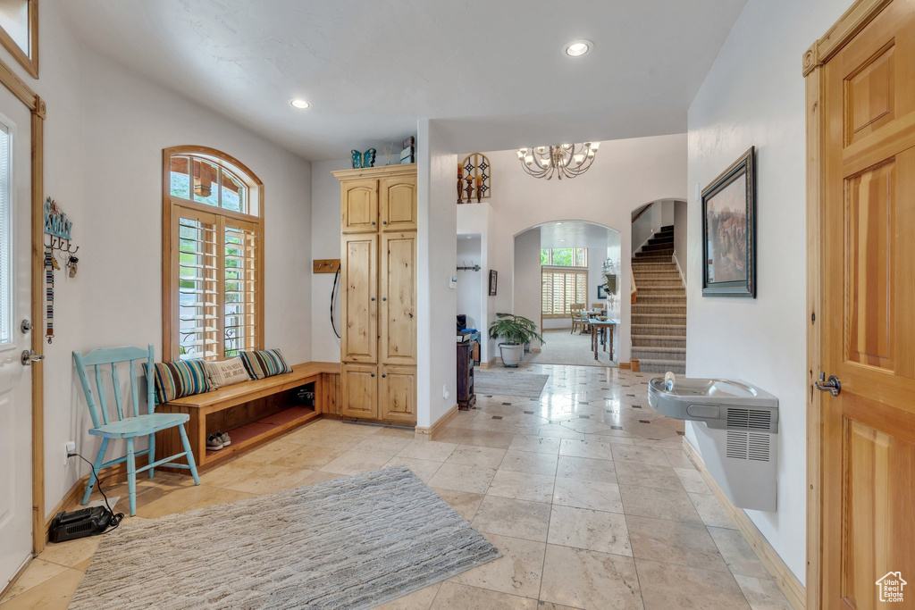 Foyer with arched walkways, baseboards, recessed lighting, stairs, and a chandelier