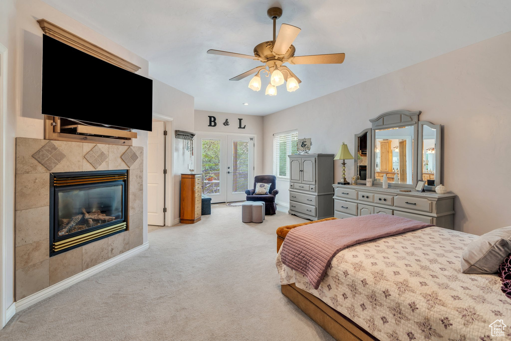 Bedroom featuring access to exterior, light carpet, french doors, a fireplace, and ceiling fan