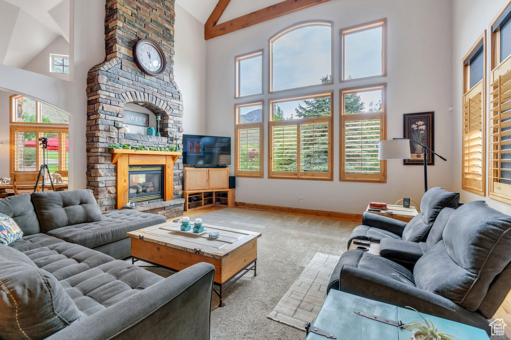 Living area featuring high vaulted ceiling, carpet floors, a fireplace, baseboards, and beamed ceiling