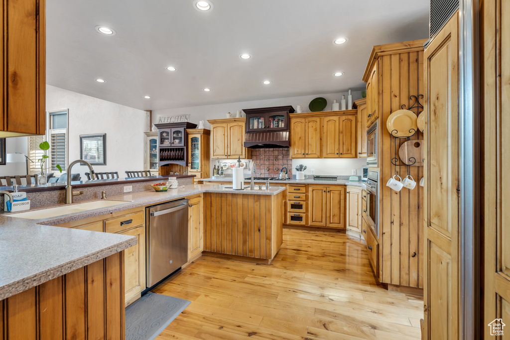 Kitchen featuring appliances with stainless steel finishes, a sink, light countertops, light wood-type flooring, and recessed lighting