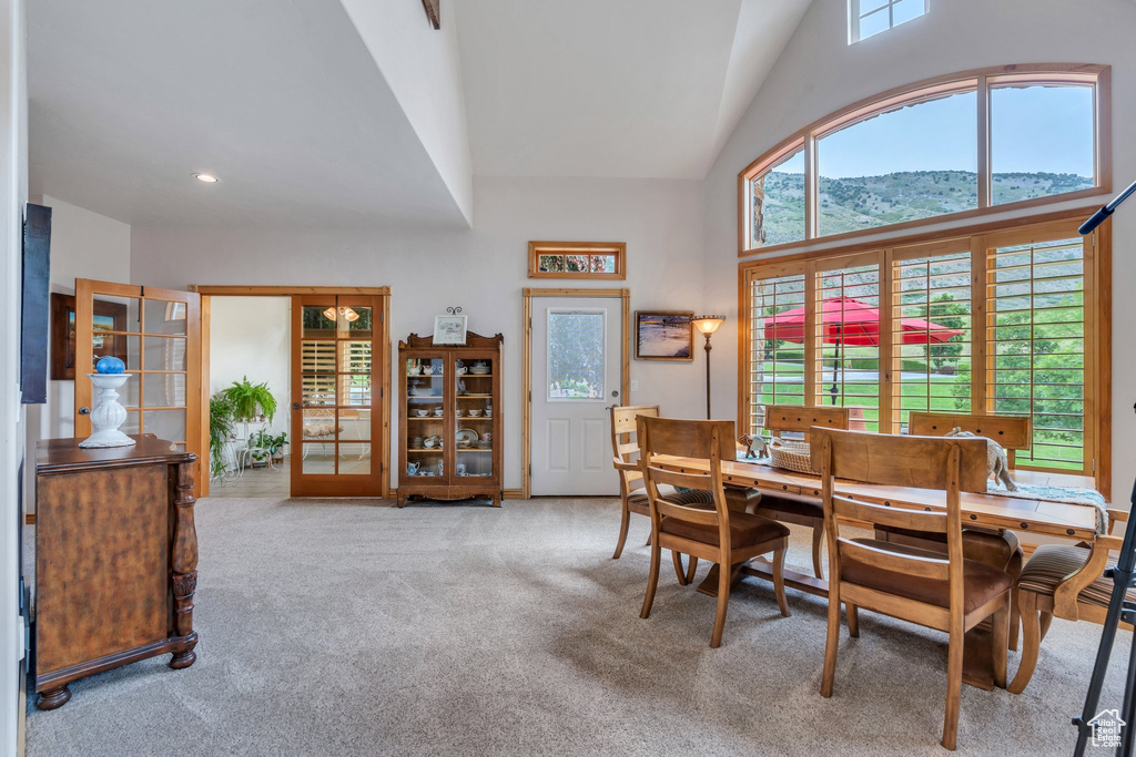 Carpeted dining room with high vaulted ceiling, recessed lighting, and a mountain view