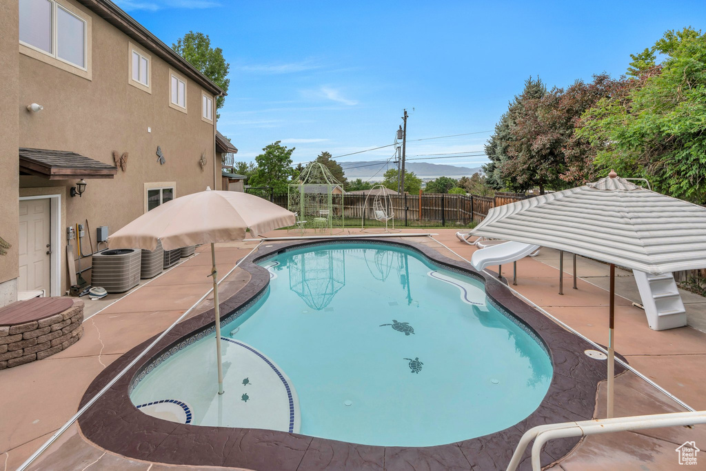 View of swimming pool with a water slide, a fenced backyard, a patio area, a gazebo, and central AC