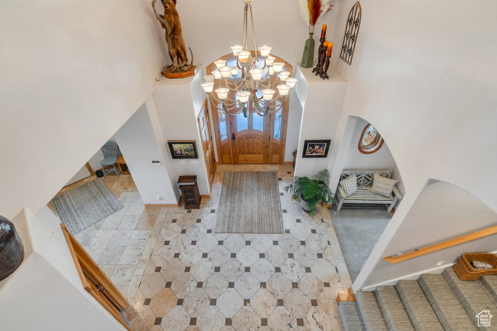 Foyer with a towering ceiling, a chandelier, stairs, arched walkways, and baseboards