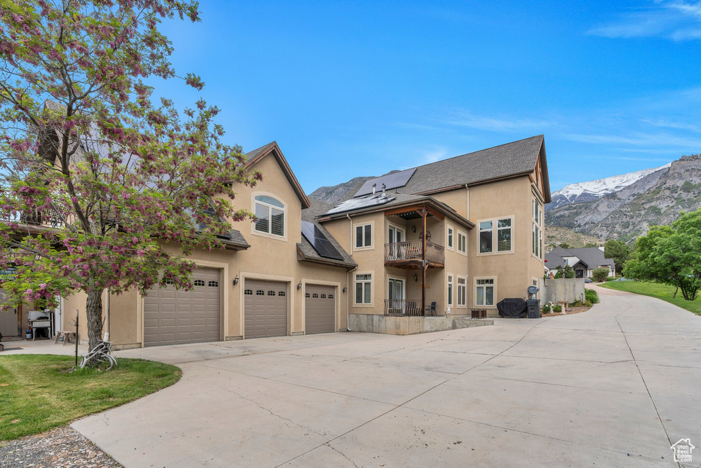 View of front facade featuring driveway, stucco siding, a garage, a balcony, and a mountain view