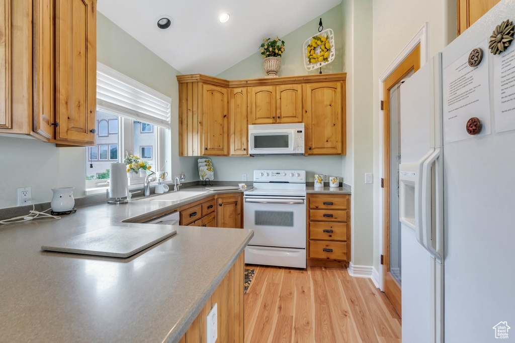 Kitchen with white appliances, a sink, light wood-type flooring, lofted ceiling, and light countertops