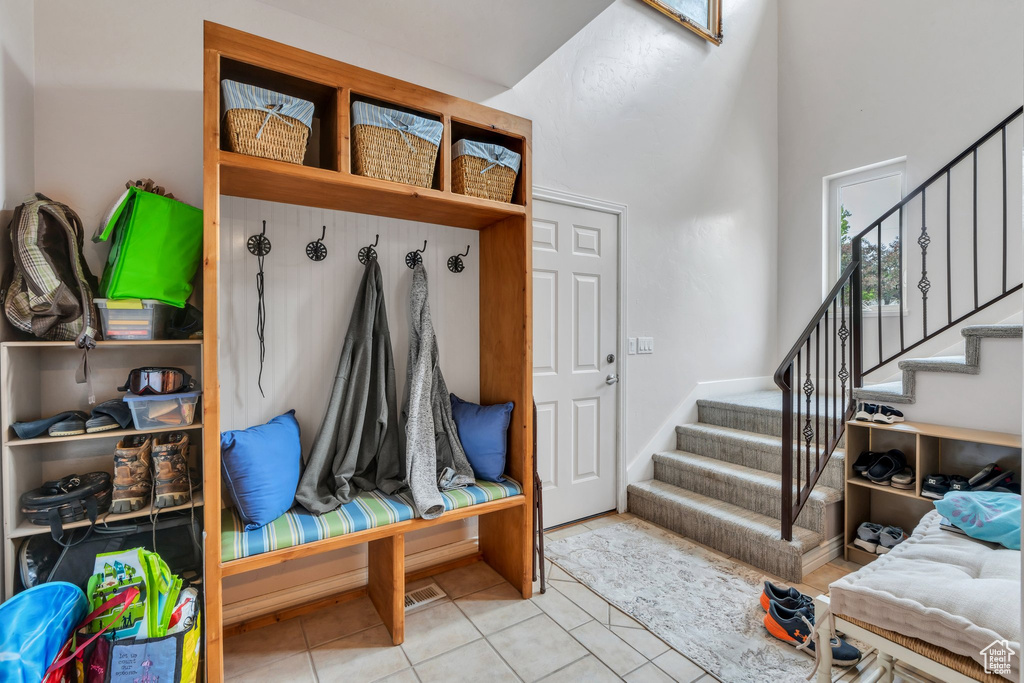 Mudroom featuring tile patterned floors and a towering ceiling