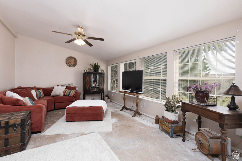 Living area with lofted ceiling, ceiling fan, unfinished concrete floors, and baseboards