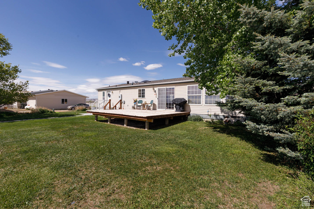 Back of house with a wooden deck and a yard