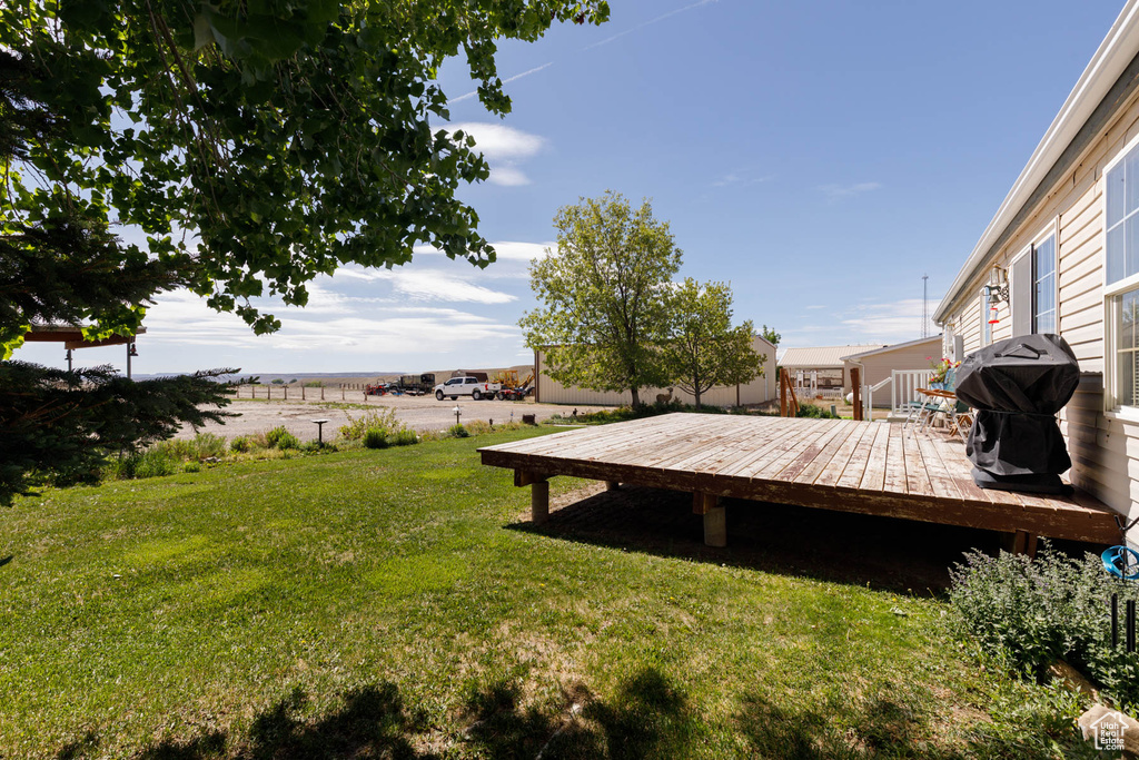 View of green lawn featuring a wooden deck