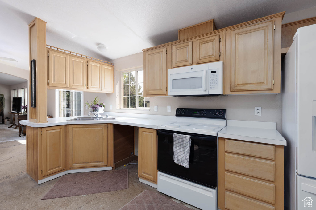 Kitchen with white appliances, light brown cabinets, a sink, light countertops, and vaulted ceiling
