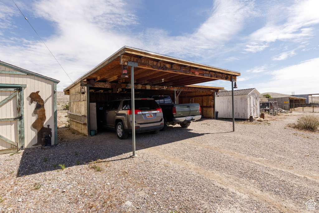 View of parking featuring a shed, a carport, and driveway