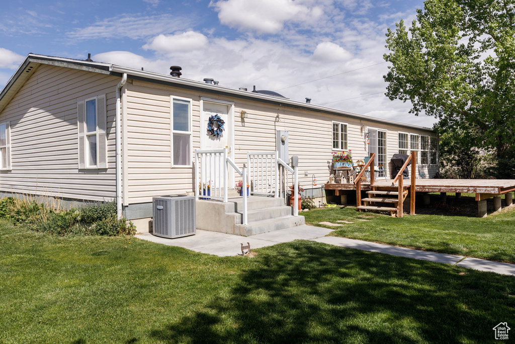 Rear view of property with central AC unit, a yard, and a deck