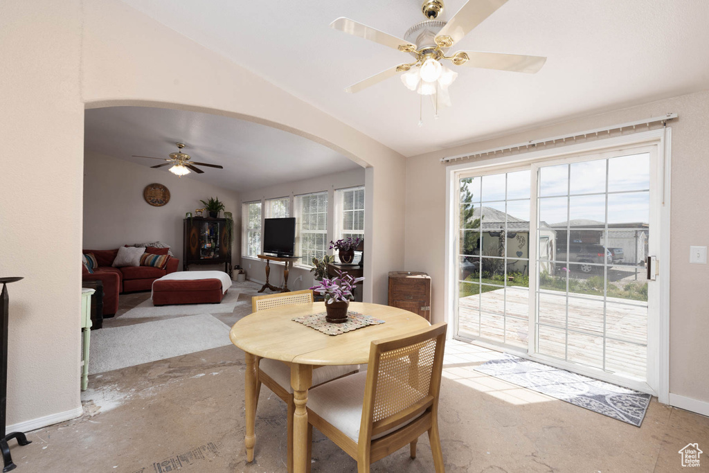 Dining space featuring ceiling fan, arched walkways, lofted ceiling, and baseboards