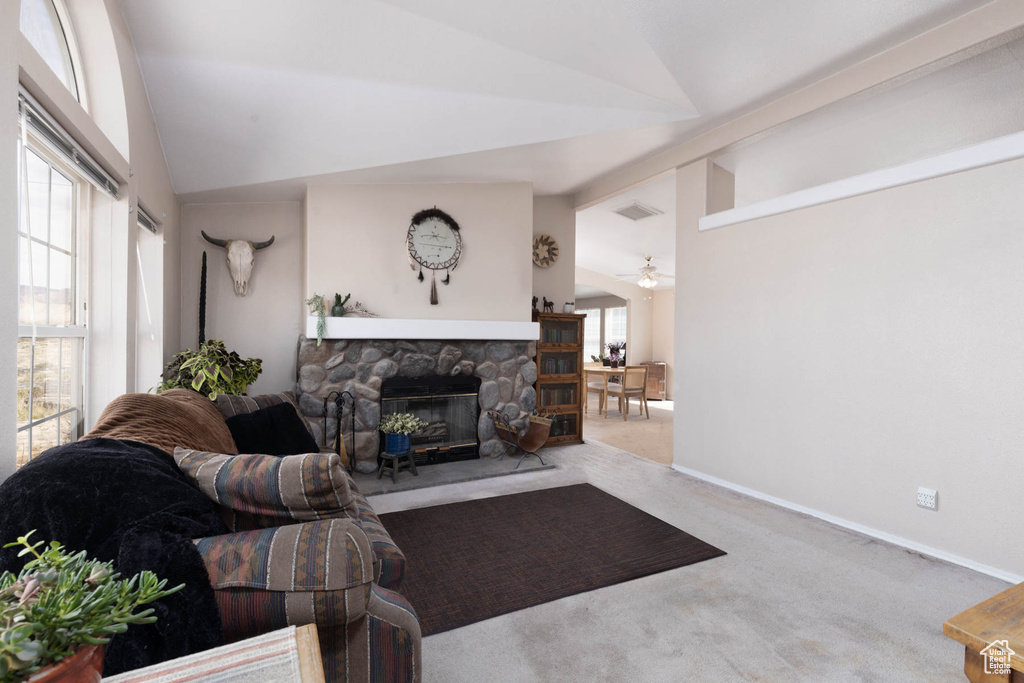 Carpeted living area featuring lofted ceiling, a fireplace, a ceiling fan, and baseboards
