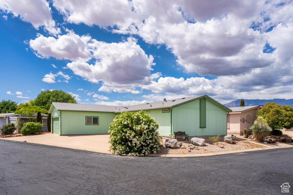 View of side of home with an attached garage, concrete driveway, and a mountain view