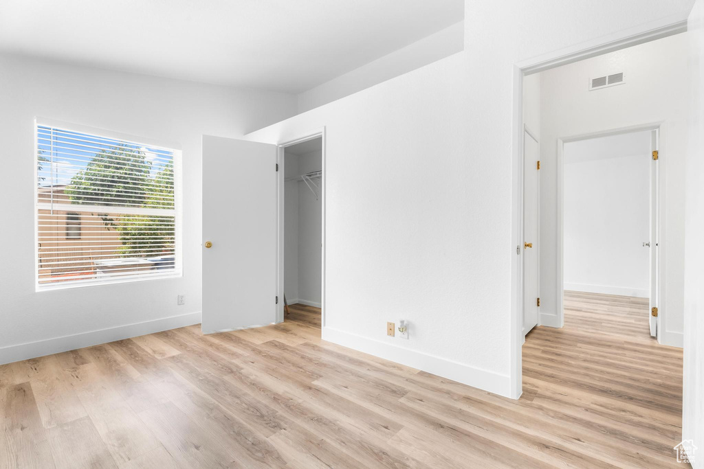 Unfurnished bedroom featuring light wood-type flooring, baseboards, and a spacious closet