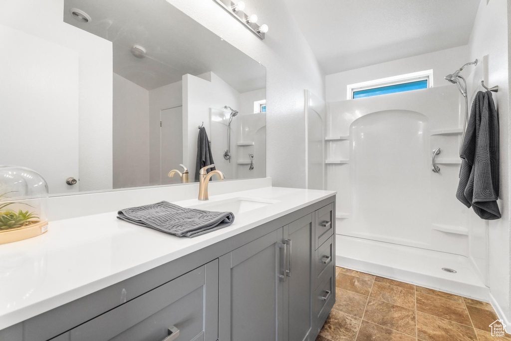 Full bathroom featuring a shower, stone finish flooring, and vanity