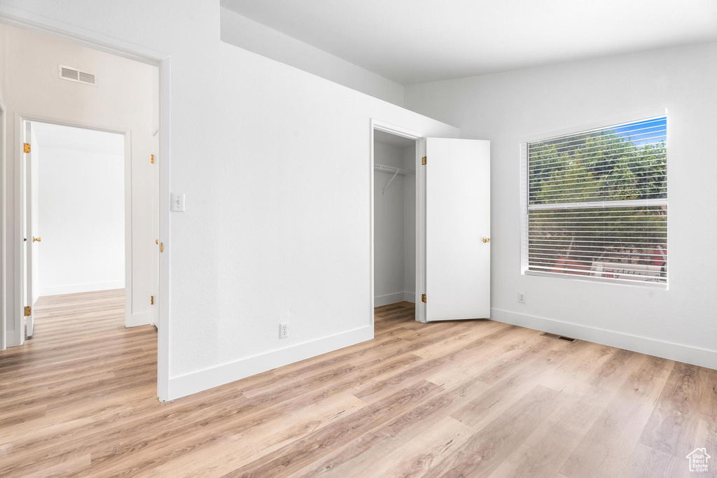 Unfurnished bedroom with light wood finished floors and baseboards