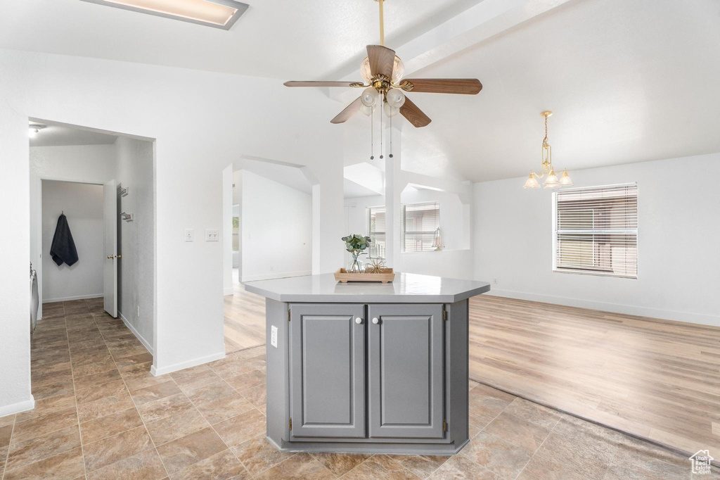 Kitchen with gray cabinetry, ceiling fan, a center island, baseboards, and high vaulted ceiling