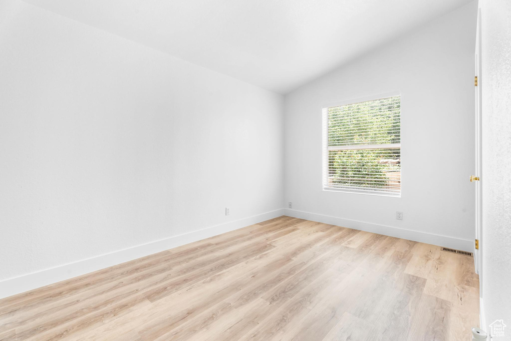 Unfurnished room with lofted ceiling, light wood-style floors, and baseboards